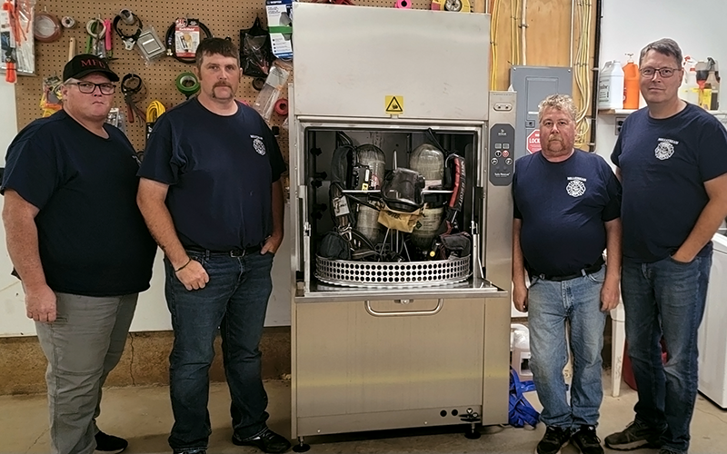 Four people standing next to a Solo Rescue decontamination machine.