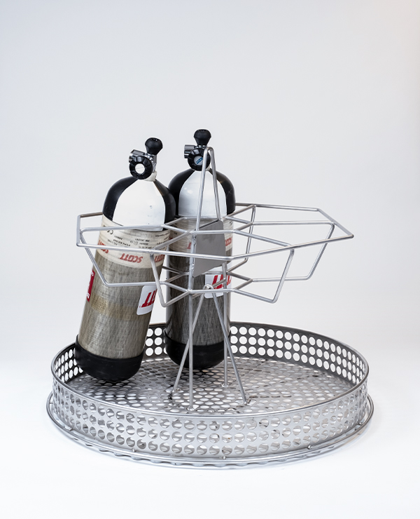 Metallbas med perforeringar som håller två Scott-gasflaskor säkrade av en stödjande metallram.