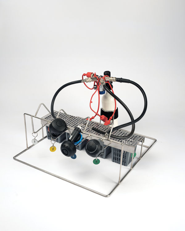 Support de valves respiratoires avec 4 emplacements, tuyaux, paniers avec étiquettes numérotées, et cylindre blanc.