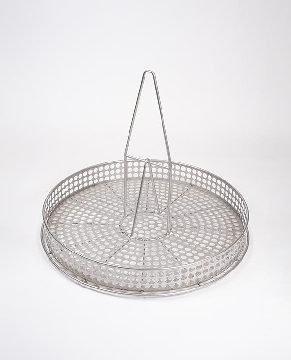 Rund perforerad metallkorg med centralt triangulärt handtag, tillverkad i rostfritt stål.