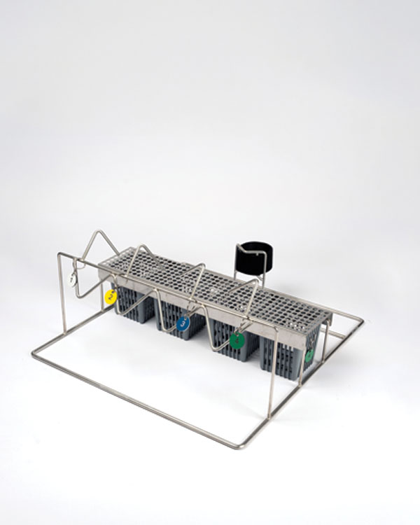 Support métallique avec compartiments, crochets et étiquettes colorées pour ranger de petites pièces d’équipement et des inserts de pression.